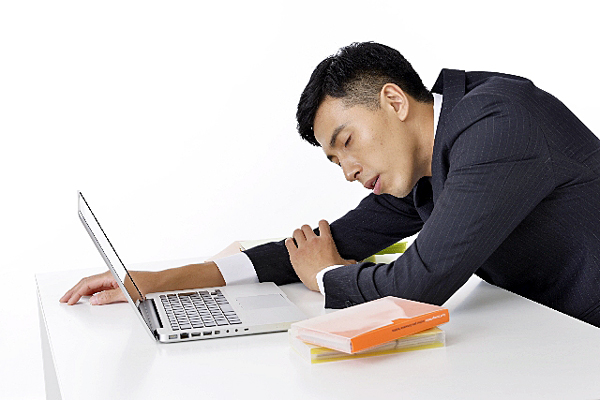 パソコンの前で寝る男性